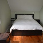 Cozy bedroom with double bed, slanted ceiling and original wide plank pine floors.