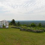 Raised beds and greenhouse and the view beyond at Cielo Farm.